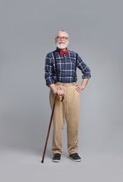 Senior man with walking cane on gray background