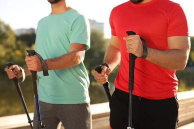 Men practicing Nordic walking with poles outdoors on sunny day, closeup