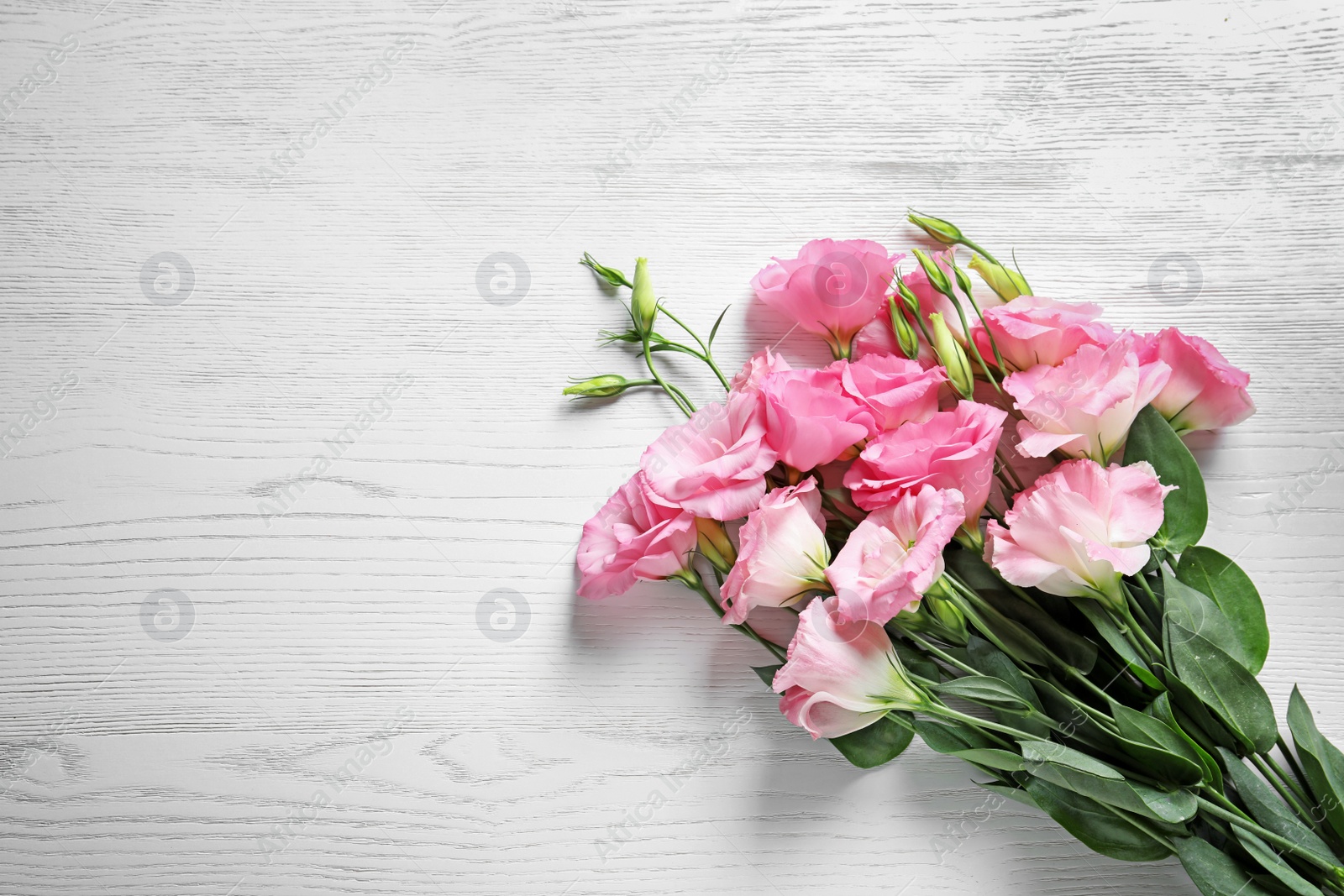 Photo of Beautiful Eustoma flowers on light wooden background