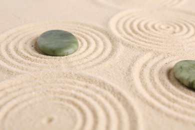 Photo of Zen garden stones on beige sand with pattern, closeup