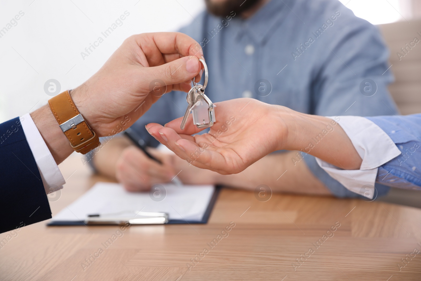 Photo of Real estate agent giving key with trinket to client in office, closeup