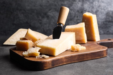 Photo of Parmesan cheese with knife on grey table