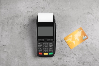 Modern payment terminal and credit card on grey background, top view. Space for text