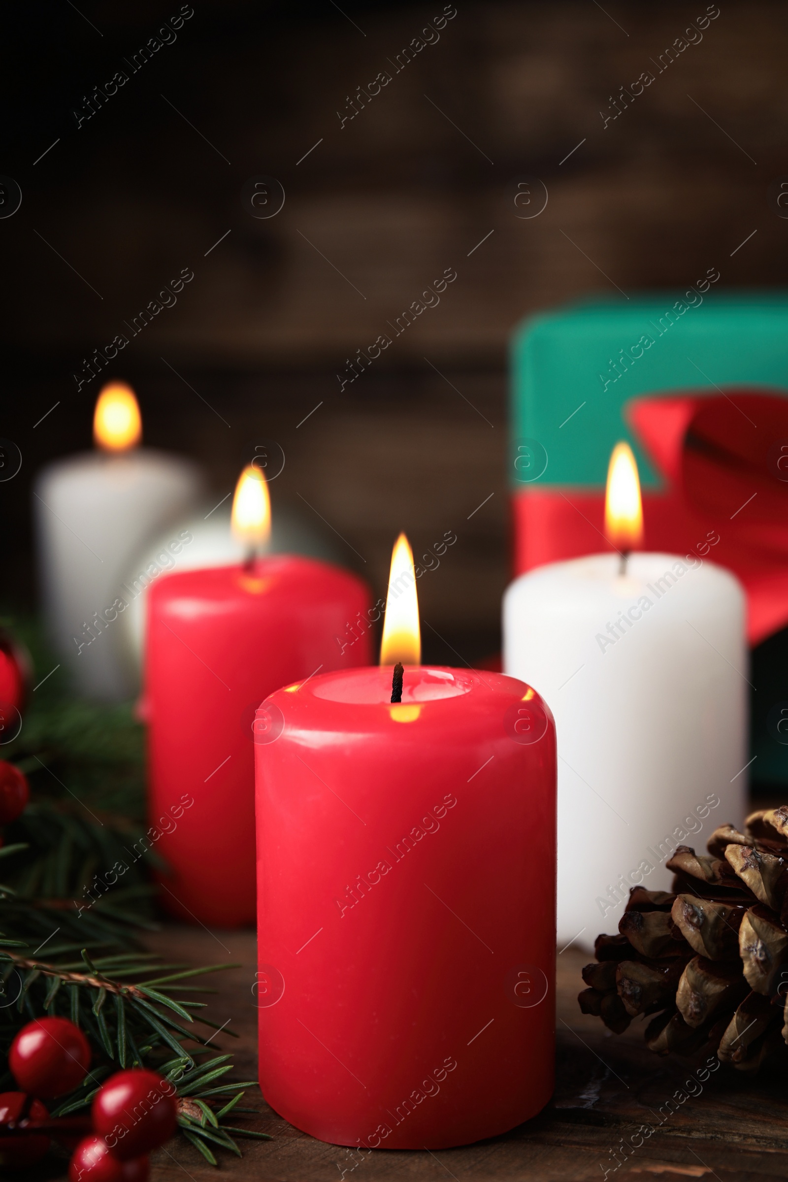 Photo of Burning candles, fir branches and pine cone on wooden table. Christmas eve