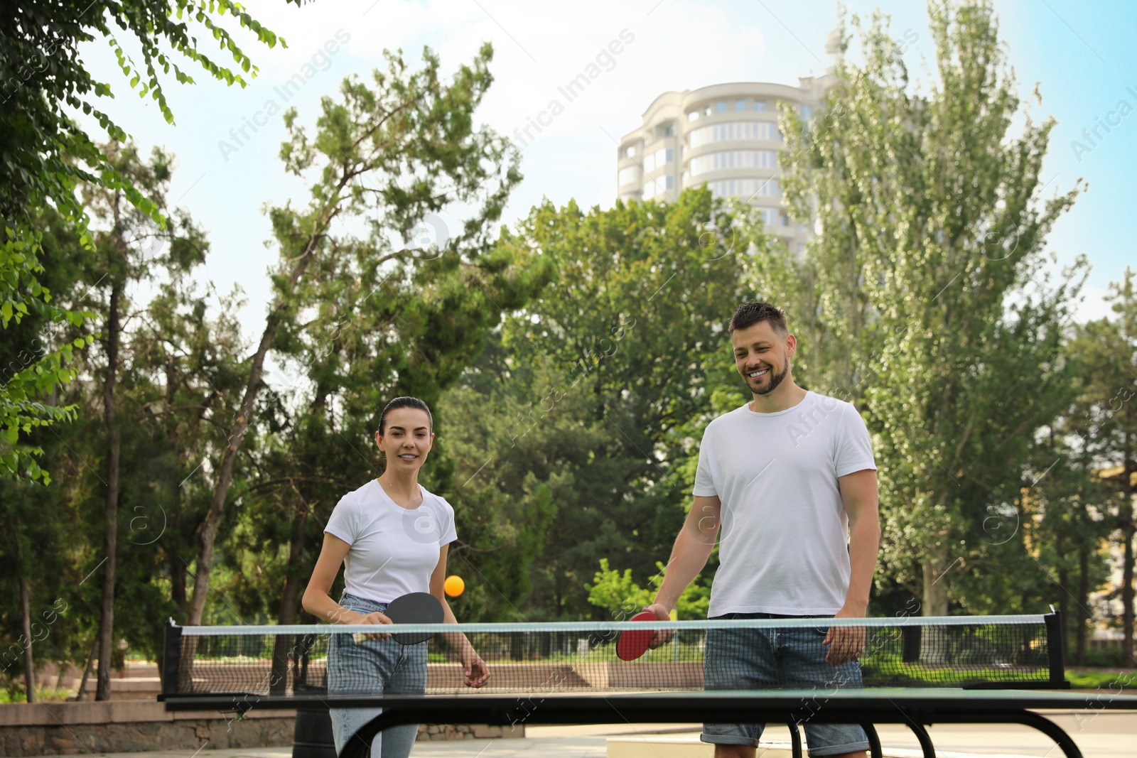 Photo of Friends playing ping pong outdoors on summer day