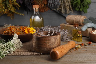 Photo of Mortar with pestle and dry lavender flowers on wooden table. Medicinal herbs