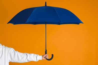 Woman with open blue umbrella on orange background, closeup