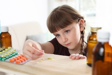 Photo of Little child taking pills from shelf at home. Danger of medicament intoxication