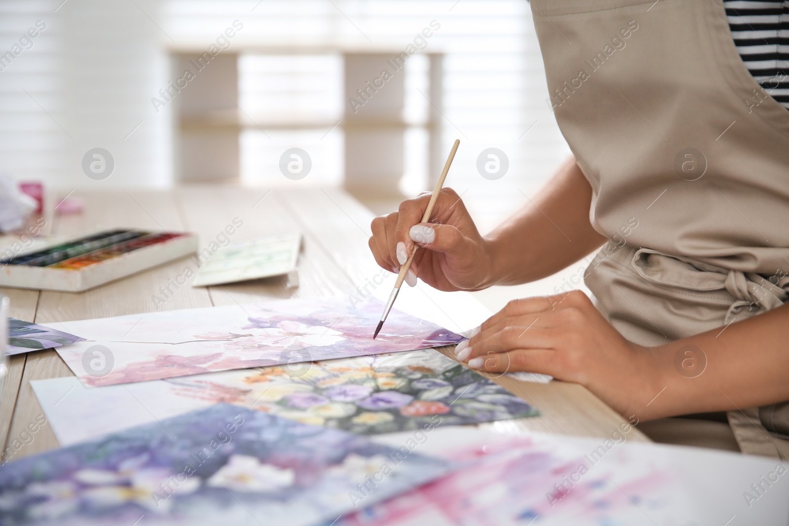 Photo of Young woman drawing flowers at table indoors, closeup. Space for text