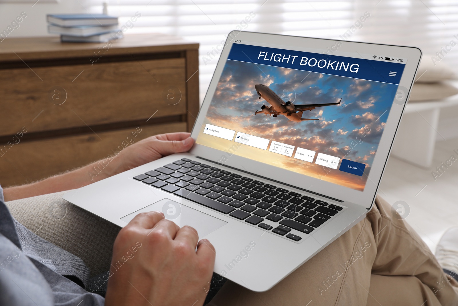 Image of Man using laptop to book flight at home, closeup