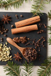 Photo of Different spices and fir branches on wooden table, flat lay