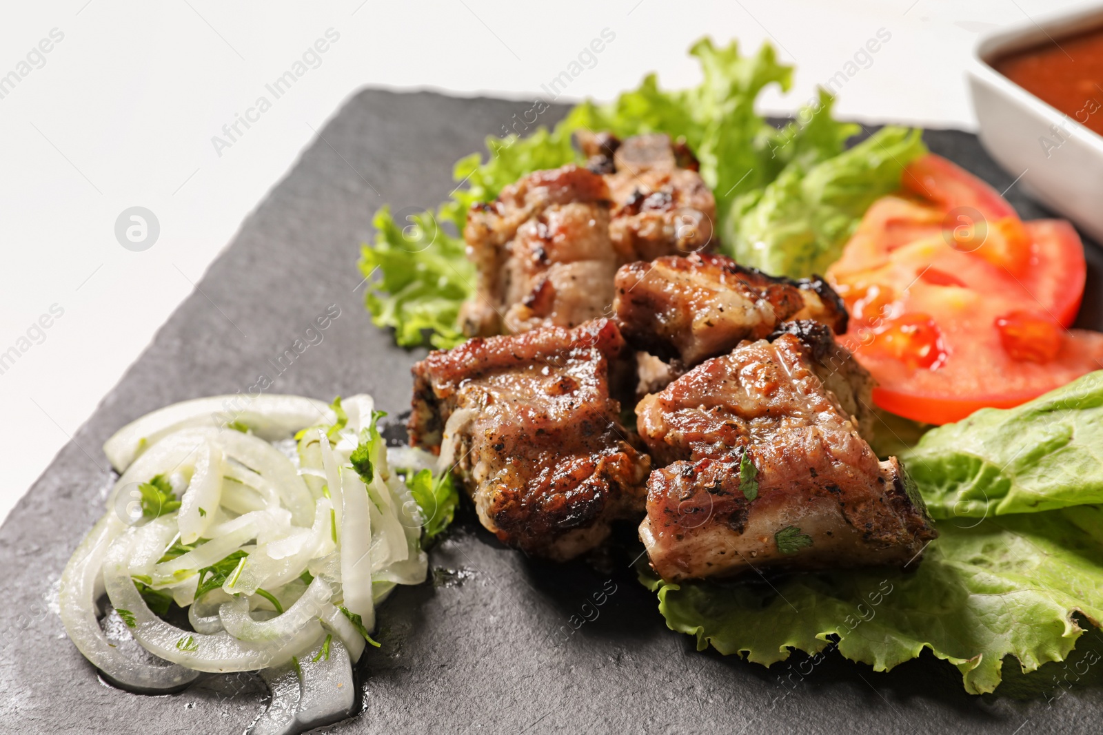 Photo of Tasty shish kebab served on slate plate, closeup