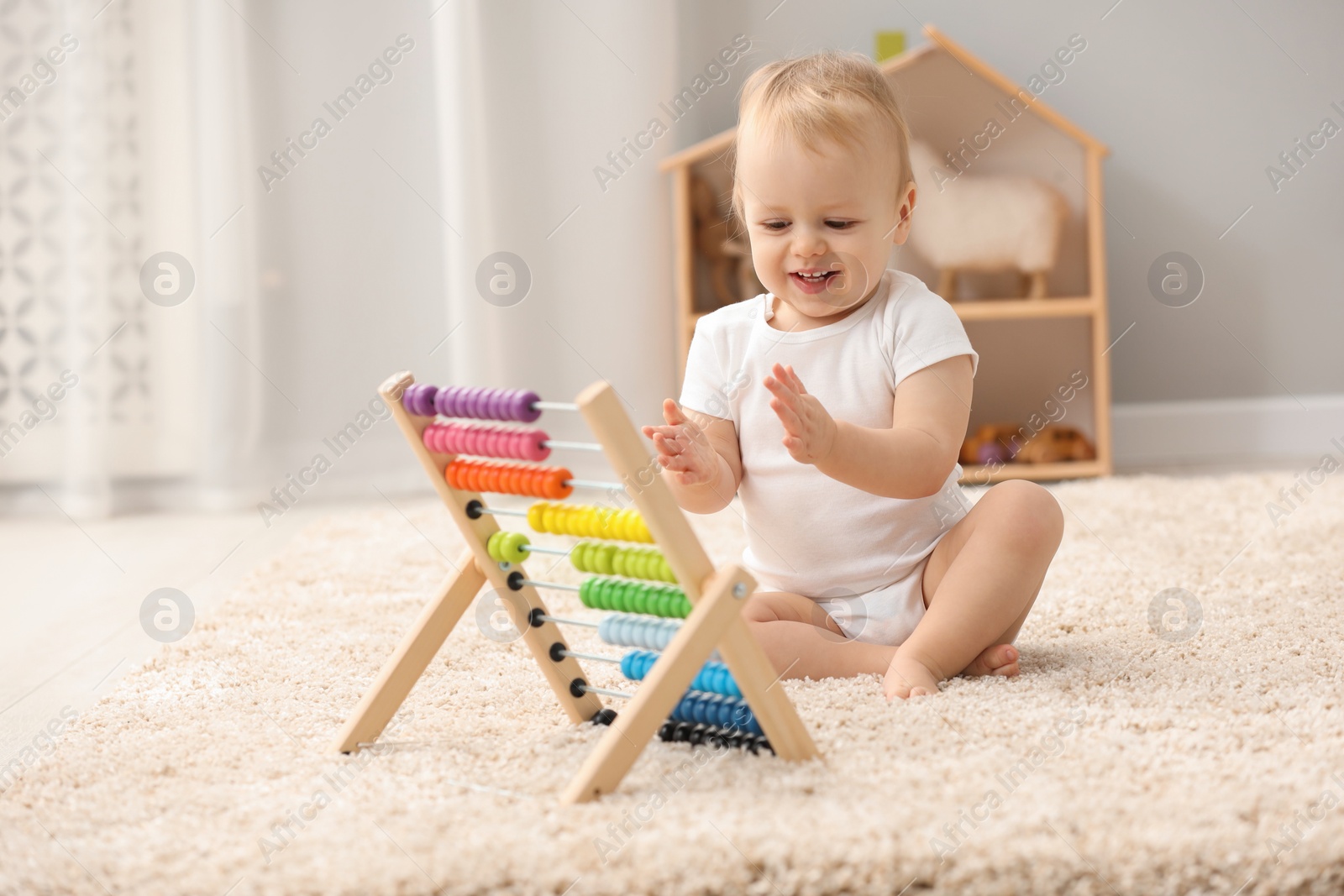 Photo of Children toys. Cute little boy playing with wooden abacus on rug at home