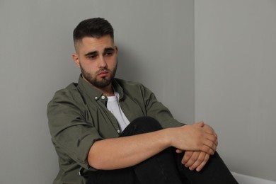 Portrait of sad man near light grey wall