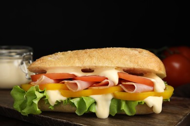 Photo of Delicious sandwich with vegetables, ham and mayonnaise on wooden table, closeup