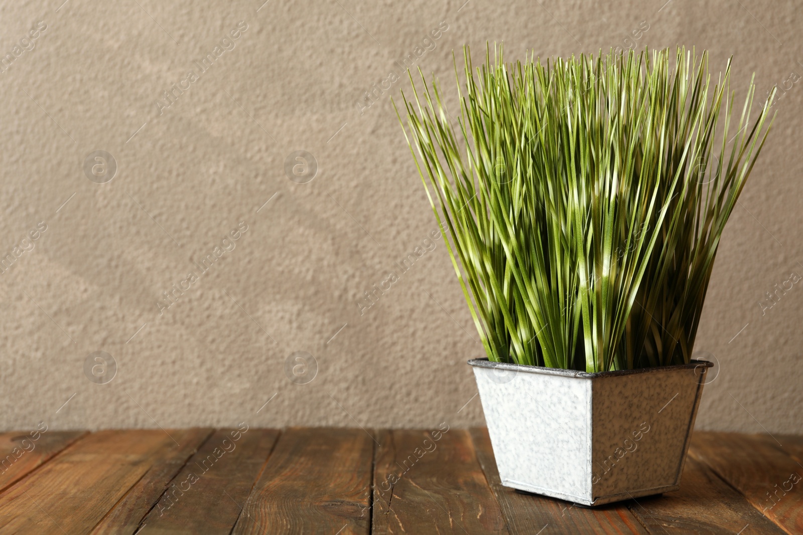Photo of Beautiful artificial plant in flower pot on wooden table against grey background. Space for text