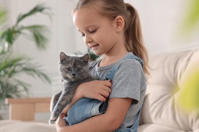 Photo of Cute little girl with kitten at home. Childhood pet
