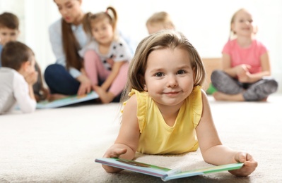 Photo of Cute little child with book indoors, space for text. Learning and playing