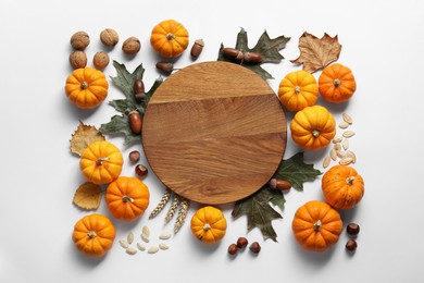Thanksgiving day. Flat lay composition with pumpkins and wooden board on white background, space for text