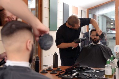 Photo of Professional hairdresser working with bearded client in barbershop