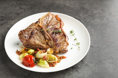 Photo of Delicious fried beef meat and vegetables on grey table