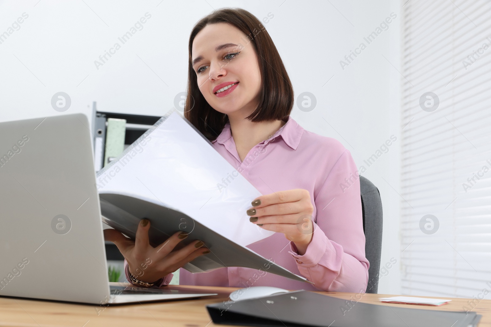 Photo of Happy young intern working at table in modern office