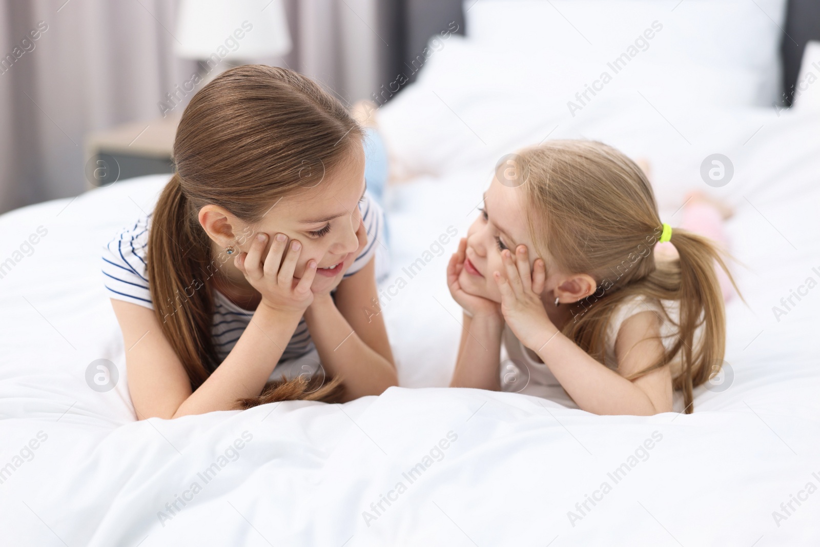 Photo of Cute little sisters on bed at home