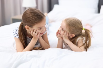 Photo of Cute little sisters on bed at home