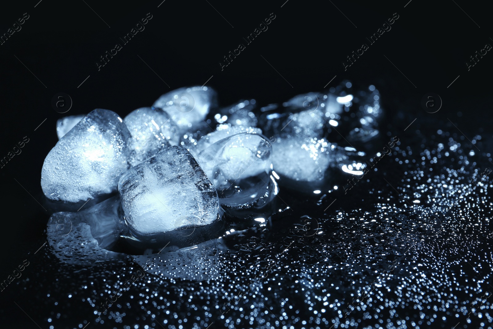 Photo of Melting ice cubes and water drops on black background. Frozen liquid