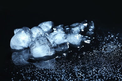 Photo of Melting ice cubes and water drops on black background. Frozen liquid