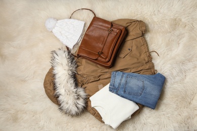 Photo of Set of stylish winter clothes on white faux fur, top view