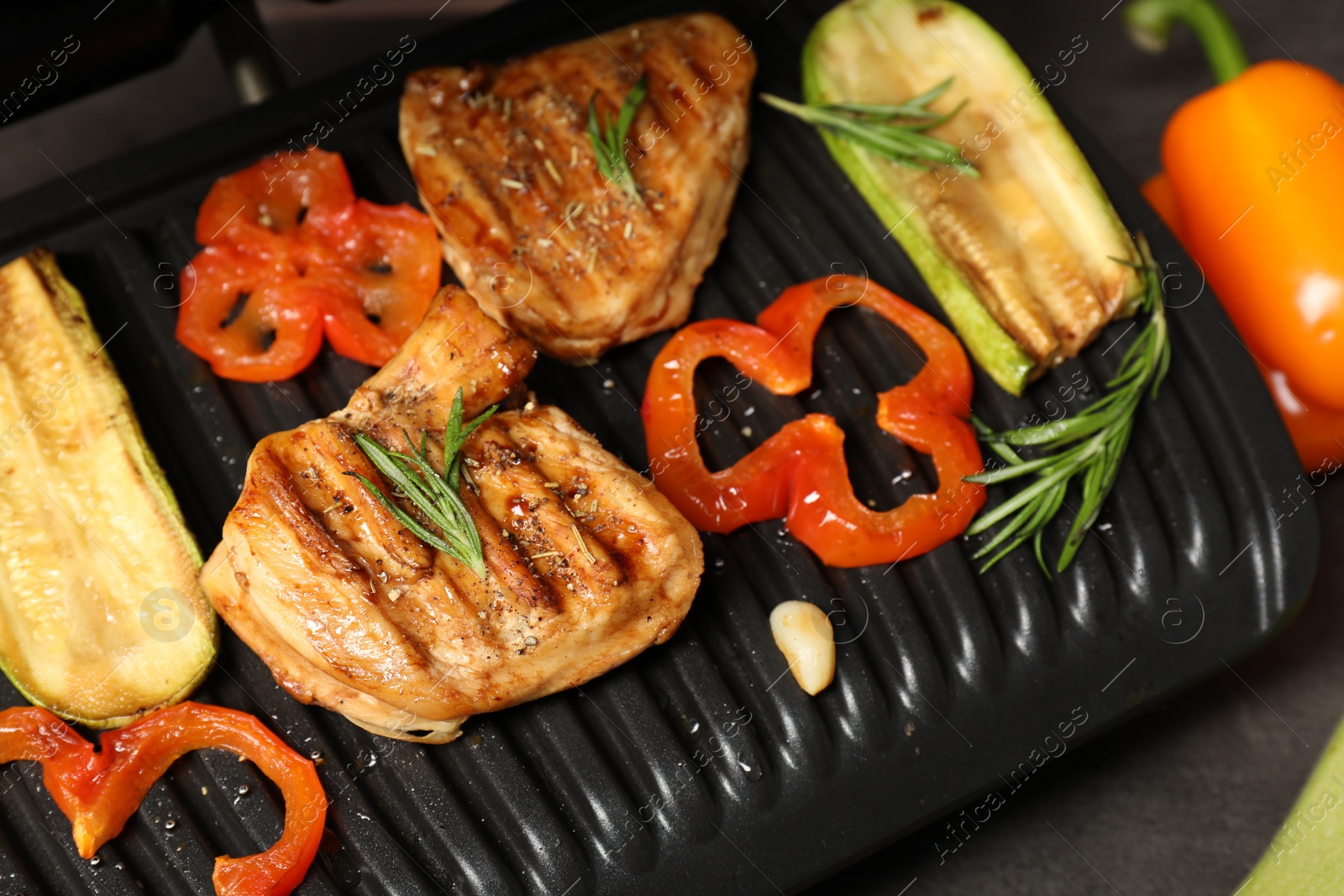 Photo of Electric grill with tasty meat, spices and vegetables on grey table, above view