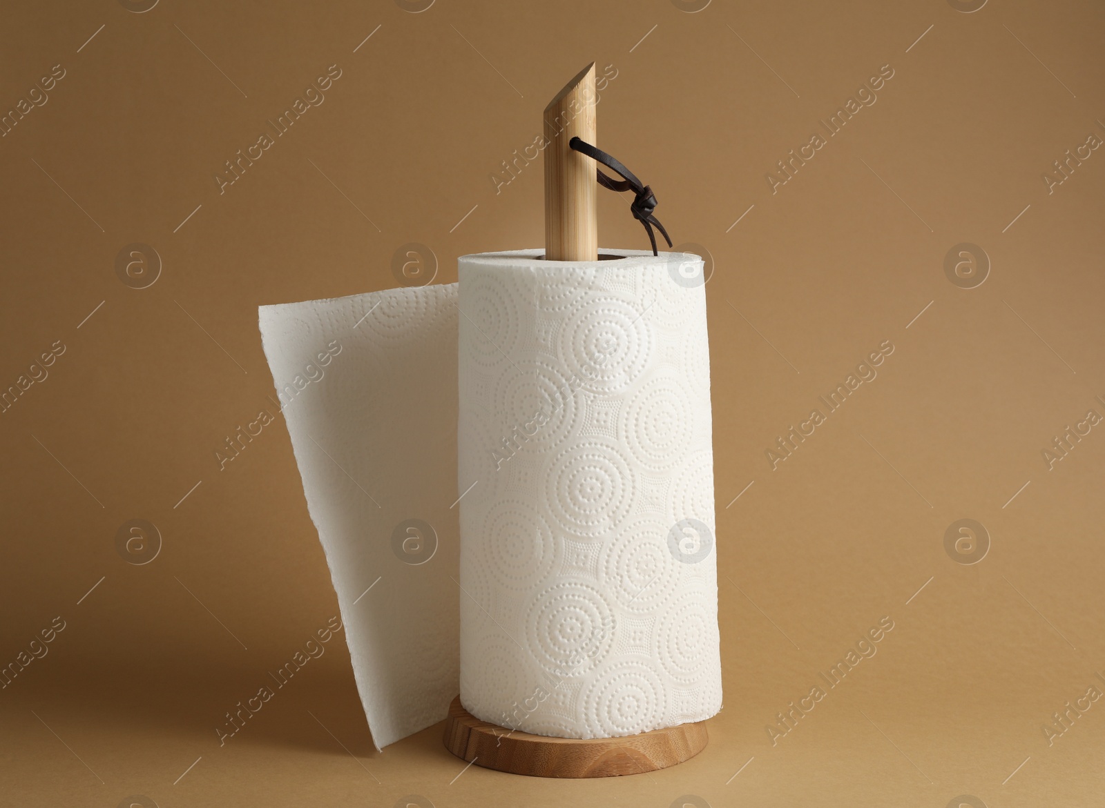 Photo of Holder with roll of white paper towels on brown background