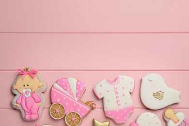 Photo of Cute tasty cookies of different shapes and space for text on pink wooden table, flat lay. Baby shower party