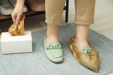 Woman wearing shoe covers onto her mules indoors, closeup