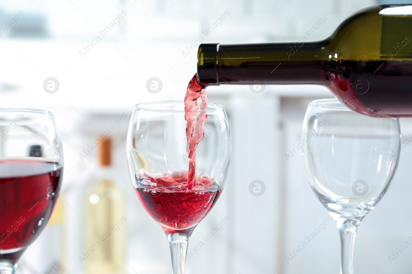 Photo of Pouring delicious red wine into glass on light background