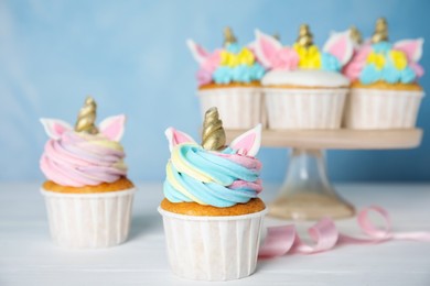 Cute sweet unicorn cupcakes on white wooden table