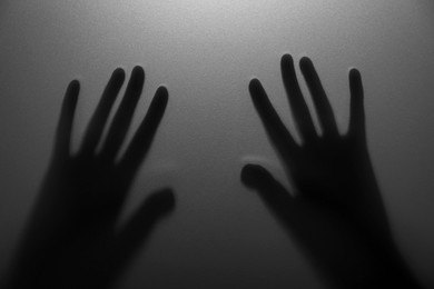 Silhouette of creepy ghost behind glass against grey background, closeup