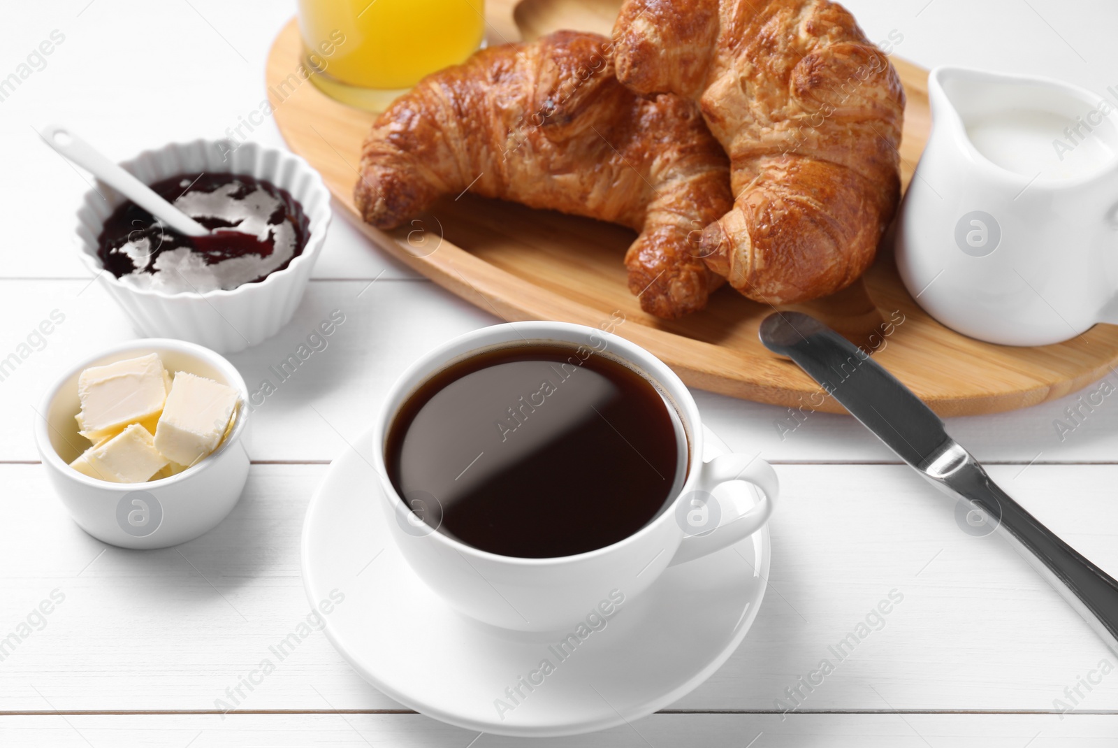 Photo of Fresh croissants, butter, jam and coffee on white wooden table. Tasty breakfast