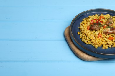 Photo of Delicious pilaf with meat, carrot and chili pepper on light blue wooden table. Space for text