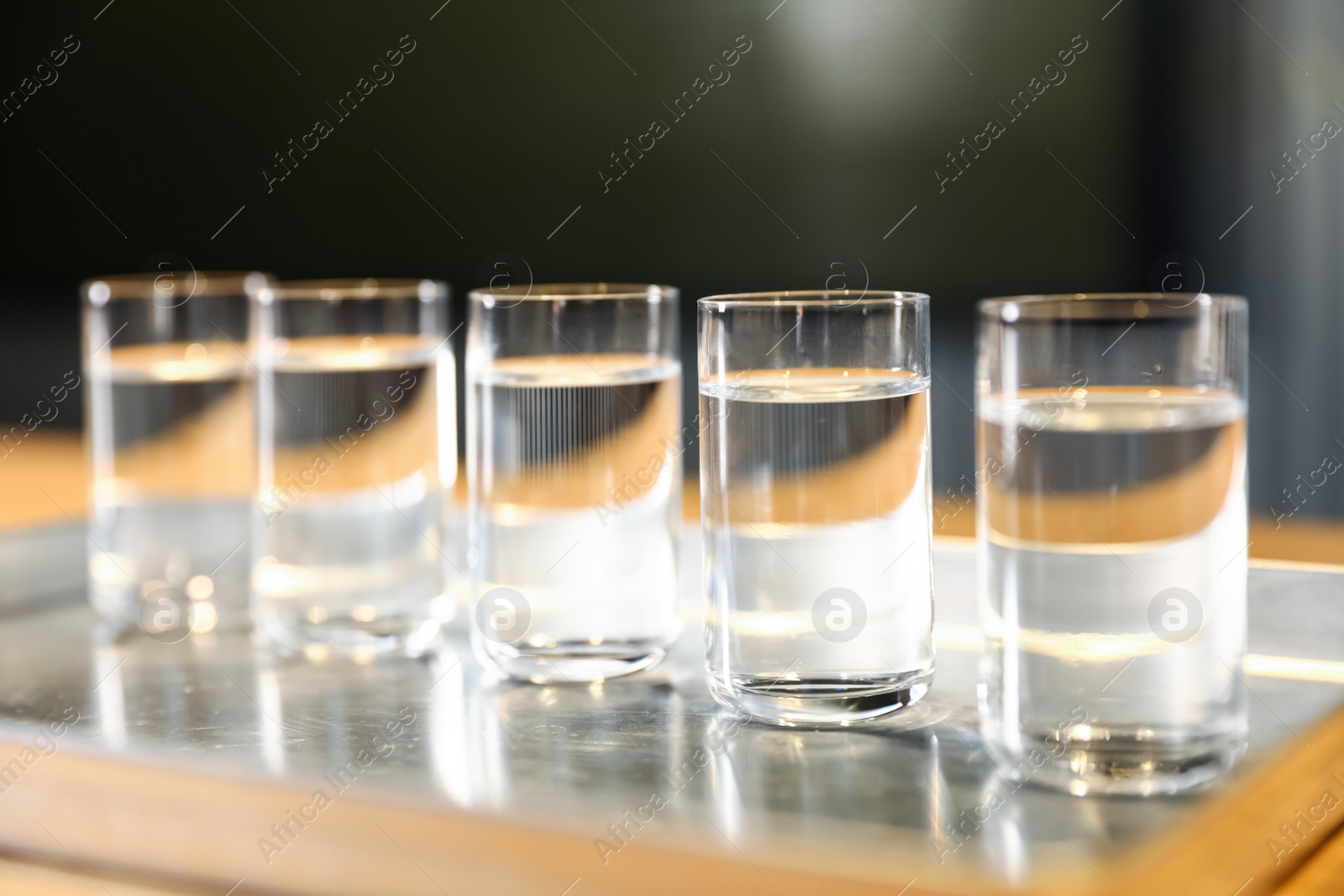 Photo of Shots of vodka on bar counter against dark background, closeup