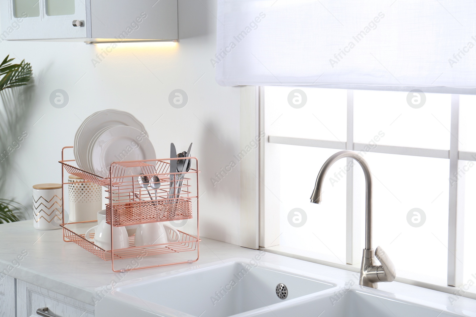 Photo of Clean dishes on drying rack in modern kitchen interior