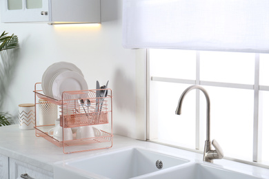 Clean dishes on drying rack in modern kitchen interior