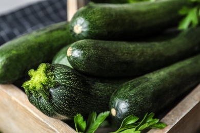 Photo of Raw green zucchinis in wooden crate, closeup