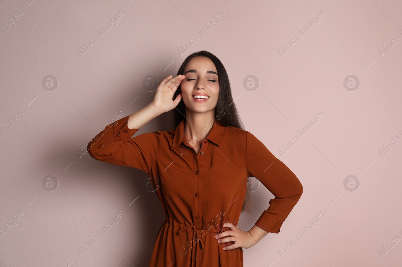 Photo of Young woman wearing stylish dress on pale pink background