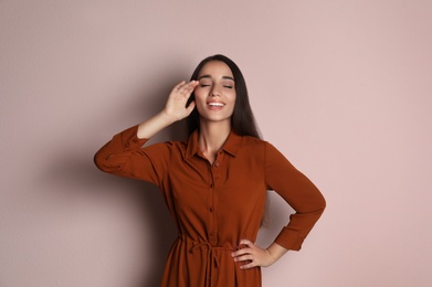 Photo of Young woman wearing stylish dress on pale pink background