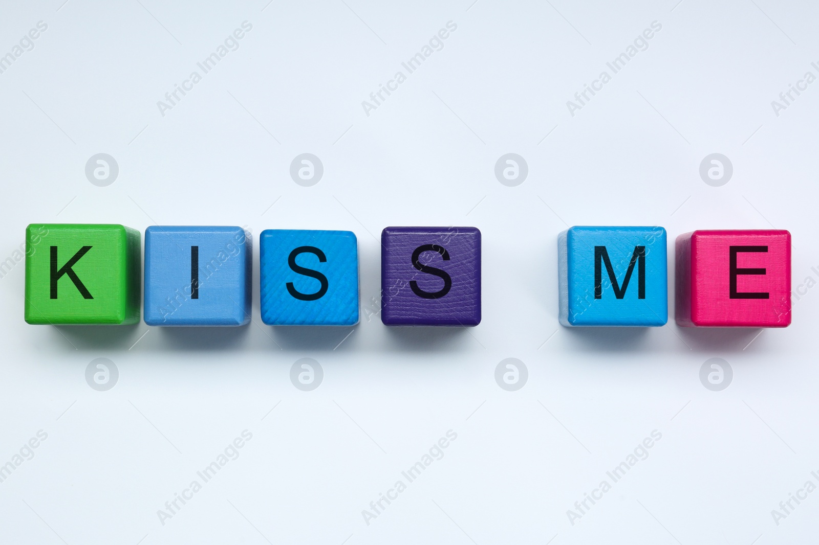 Photo of Colorful cubes with phrase Kiss Me on white background, flat lay