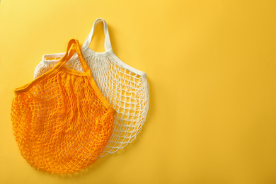 Photo of Empty net bags on yellow background, flat lay. Space for text