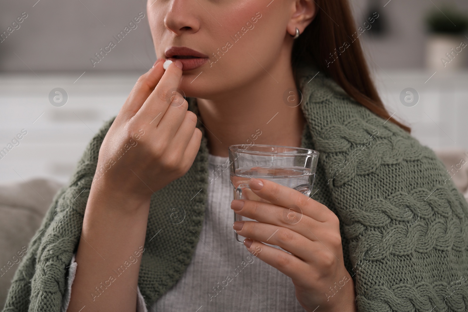 Photo of Woman with glass of water taking antidepressant pill on blurred background, closeup