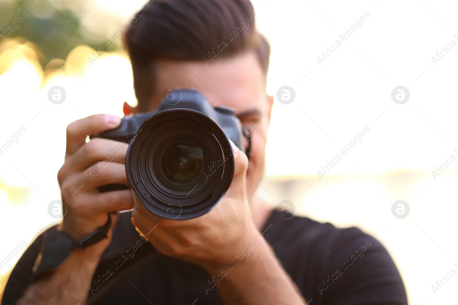 Photo of Photographer taking picture with professional camera in countryside, focus on lens